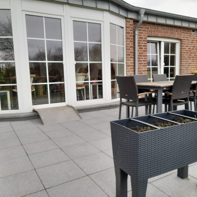 schöne Terasse Terrasse mit Tischen, Stühlen und einem Pflanzkübel im Vordergrund.